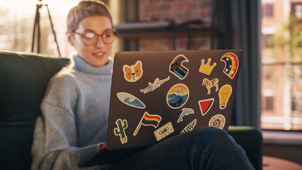 A person uses a laptop with several custom stickers