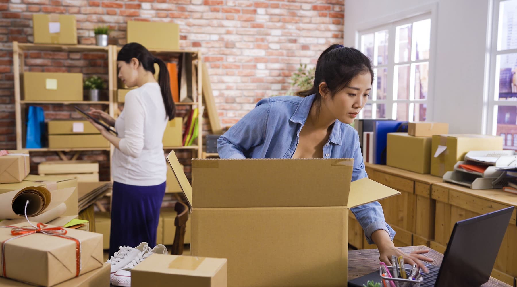 Two women business owners packing products for shipment