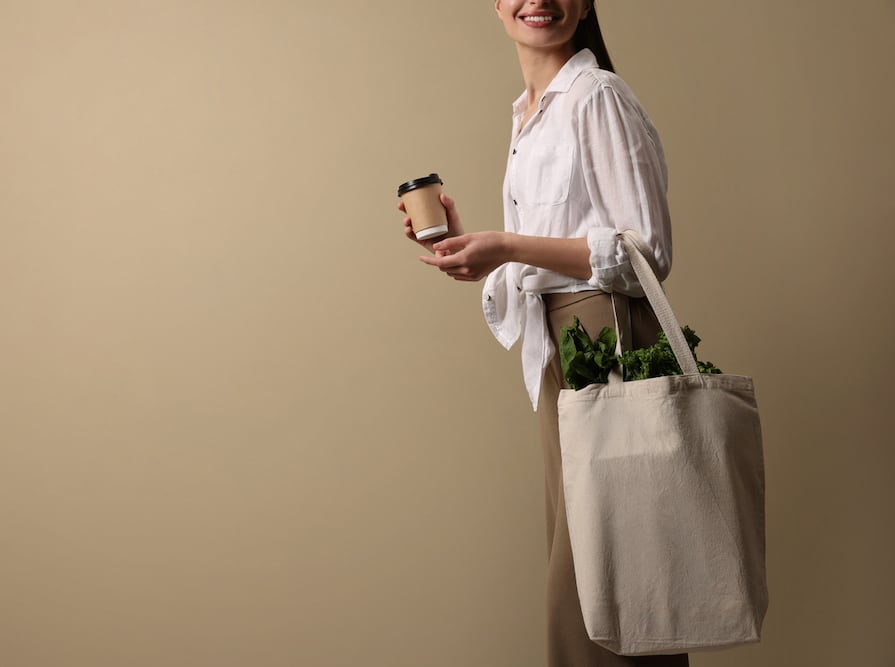 A woman carrying a coffee and tote bag