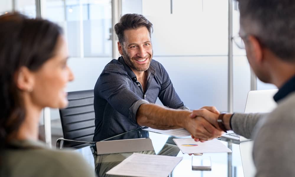 Two business people shake hands during a meeting