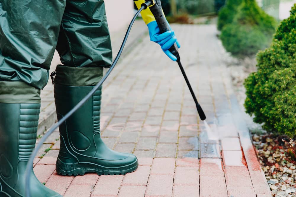A pressure washing worker cleans a walkway