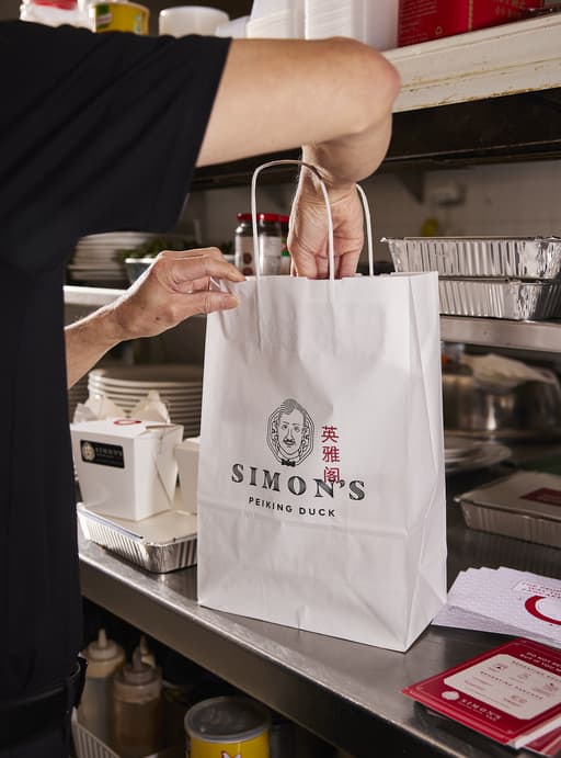 A person packs a custom take-out bag
