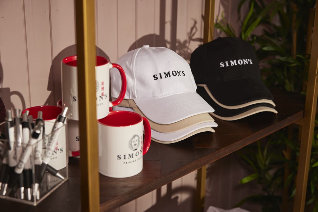 A shelf with branded merch items including hats, mugs and pens