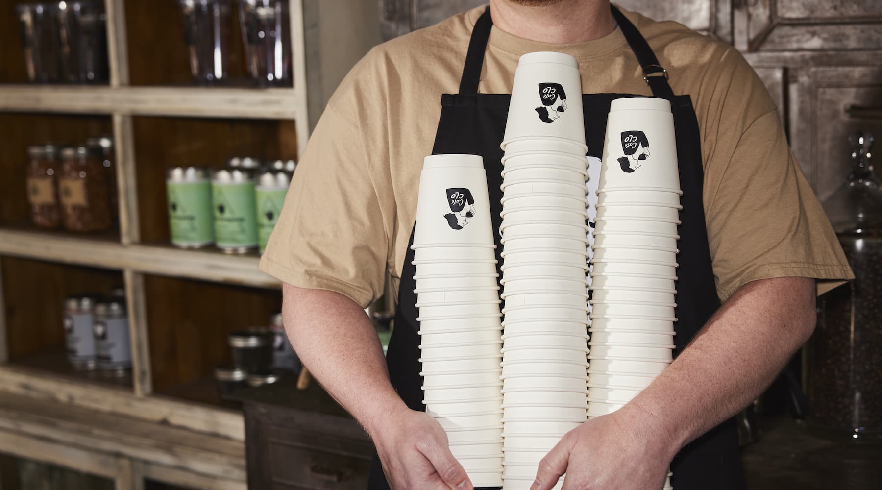 A cafe worker holding branded coffee cups